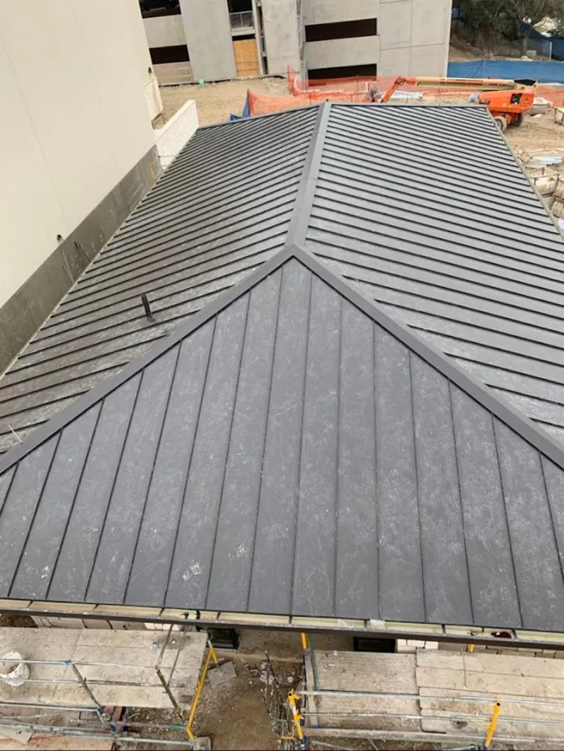 Commercial metal roof construction with crane equipment in Nashua